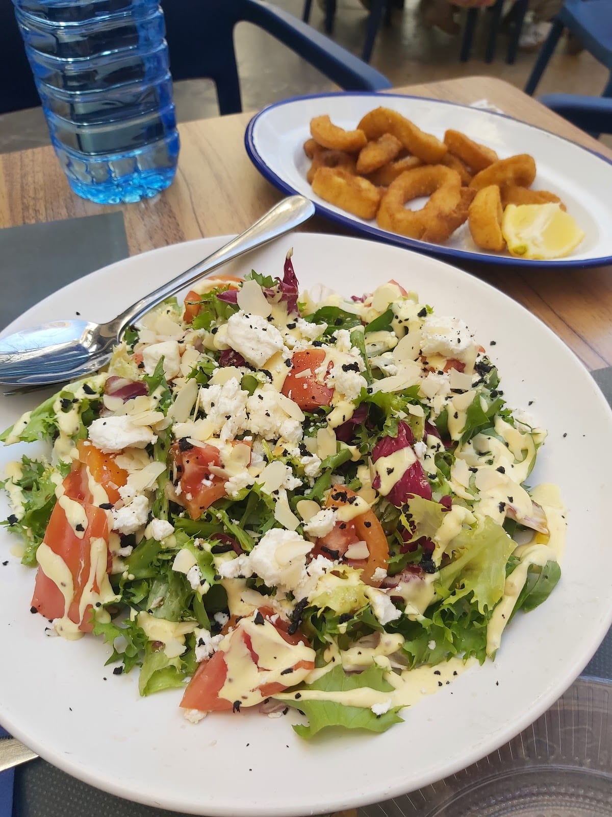 Ensalada con queso feta, almendra laminada y aliño de mostaza, con calamares rebozados al fondo