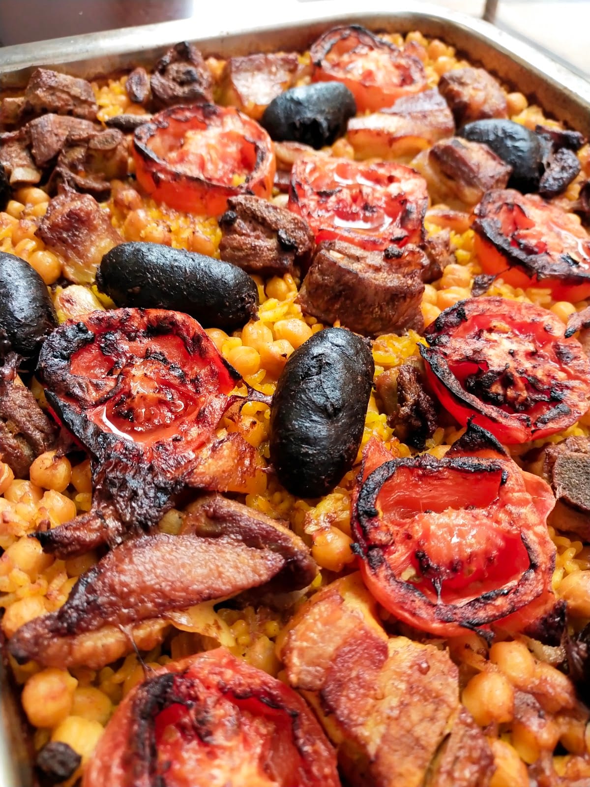 Arroz al horno en bandeja con morcilla, tomates asados, costilla y garbanzos