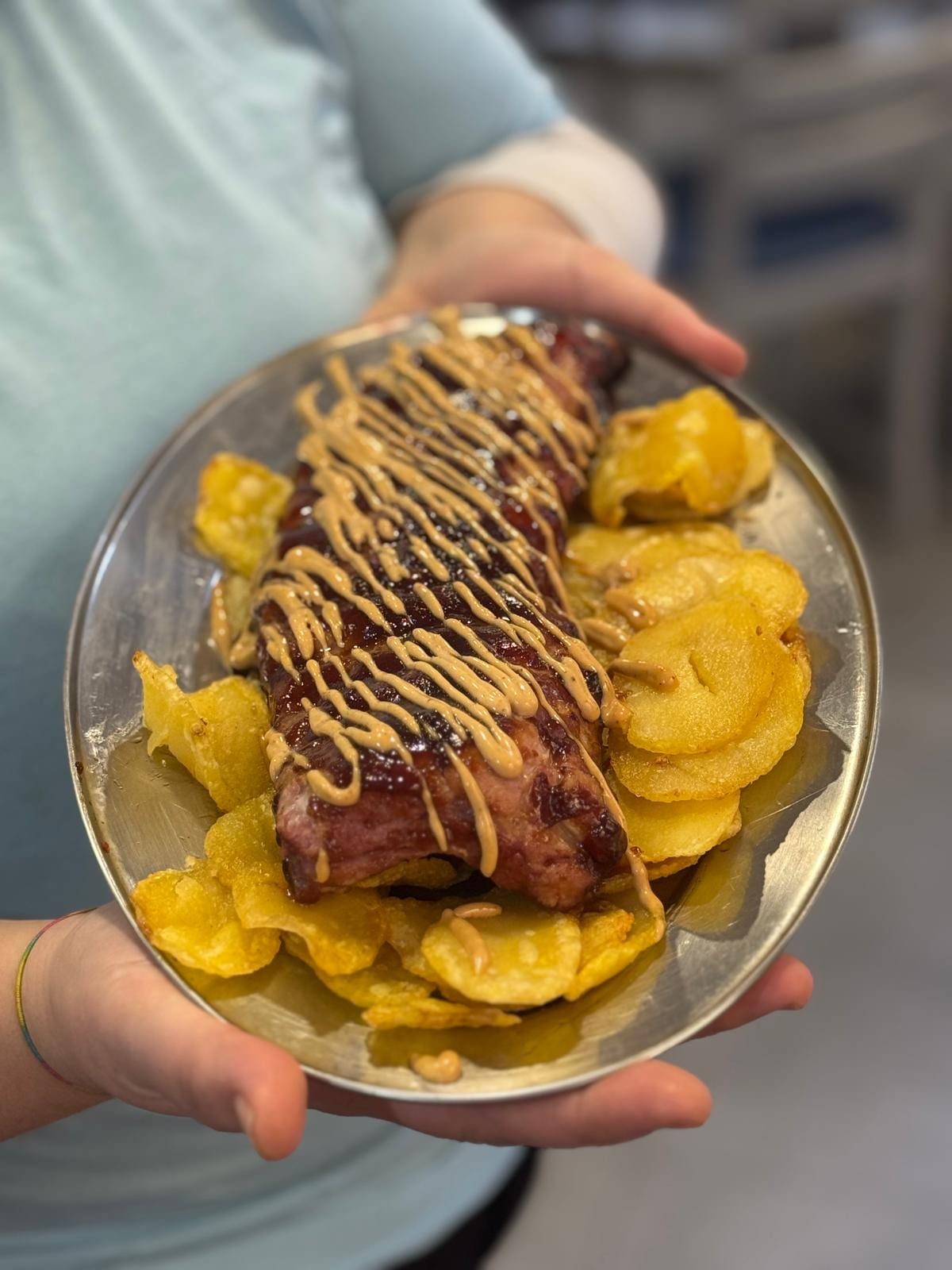 Costillas a baja temperatura con salsa y patatas panadera en una bandeja metálica