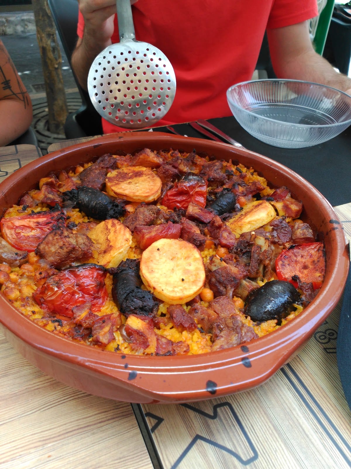 Arroz al horno en cazuela de barro con morcilla, tomate asado, patata y garbanzos
